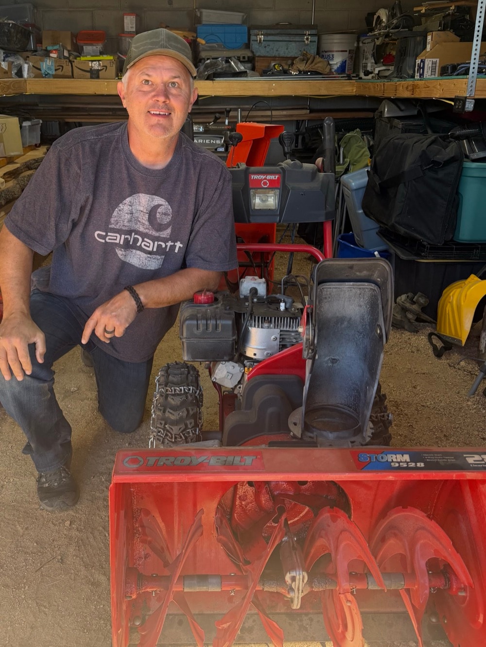 Jim kneeling beside a Troy-Bilt snowblower in his shop