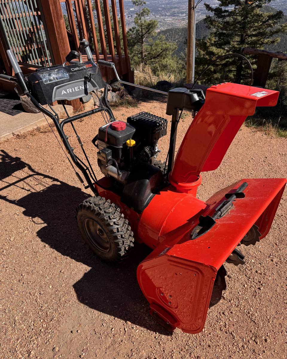 Orange Ariens Deluxe 28 two-stage snowblower on a gravel drive